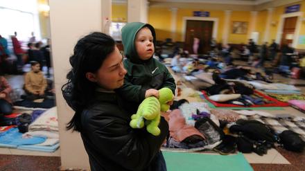 Eine Mutter auf der Flucht trägt ihr Kind in einem Raum für Frauen und Kinder.