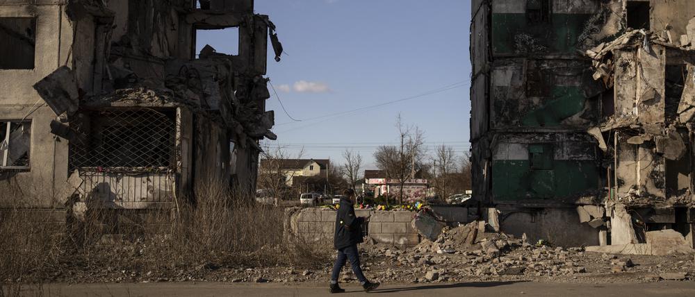Ein Mann geht an einem Wohnblock vorbei, dessen Mittelteil nach einem Luftangriff vor einem Jahr fehlt (Symbolbild).