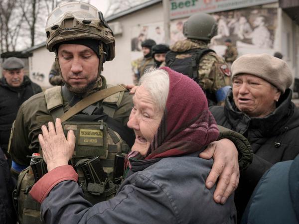 Eine Frau umarmt einen ukrainischen Soldaten, nachdem ein Konvoi von Militär- und Hilfsfahrzeugen in Butscha eingetroffen ist.