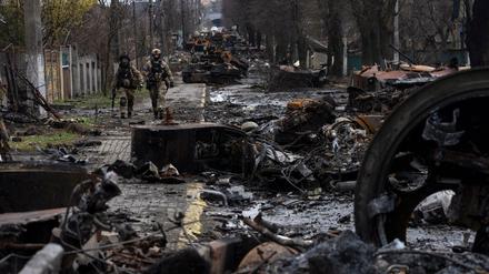 Zwei ukrainische Soldaten gehen durch die zerstörte Stadt Butscha. 