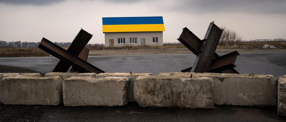 Panzersperren bei einem Haus in den Farben der ukrainischen Flagge nahe Kiew