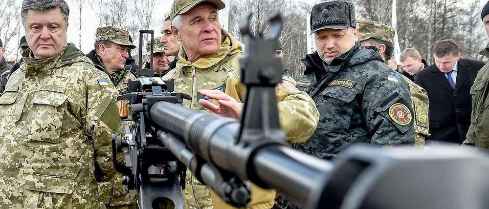 Die Waffenruhe in der Ukraine ist brüchig. Am Wochenende starben bei drei Vorfällen neun Soldaten. Präsident Petro Poroschenko (links) inspizierte am Samstag in Uniform Waffen der Nationalgarde.