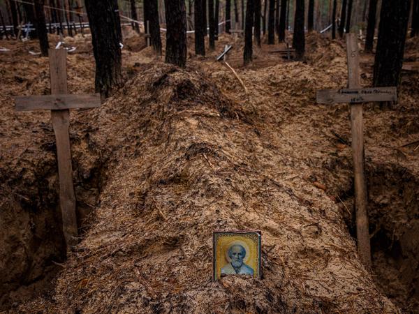 Eine orthodoxe Ikone steht neben leeren Gräbern, die nach der Exhumierung von Leichen aus Massengräbern in der Stadt Isjum ausgehoben wurden.