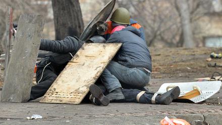 Demonstranten im Zentrum von Kiew schirmen die Leiche eines erschossenen Mit-Demonstranten ab.