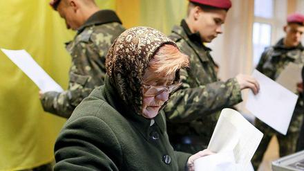 Eine Frau und mehrere Soldaten bei der Parlamentswahl in Kiew. 