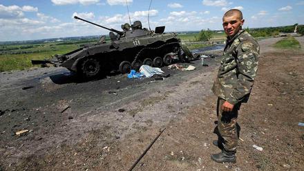 Ein ukrainischer Soldat steht vor einem ausgebrannten Panzerfahrzeug pro-russischer Separatisten. Am Samstag hat die Armee die umkämpfte Stadt Slowiansk nach eigenen Angaben zurückerobert. 