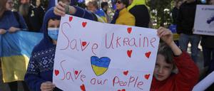 Kinder halten bei einer Demonstration für den Frieden ein Plakat mit der Aufschrift „Rettet die Ukraine, rettet unsere Menschen“.