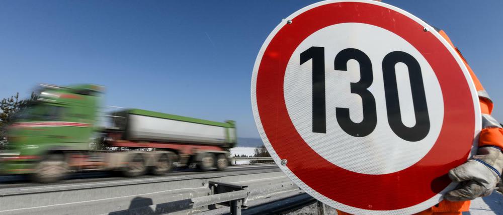 Ein Straßenwärter hält an der Autobahn A81 ein Schild mit der Aufschrift "130" in den Händen. 