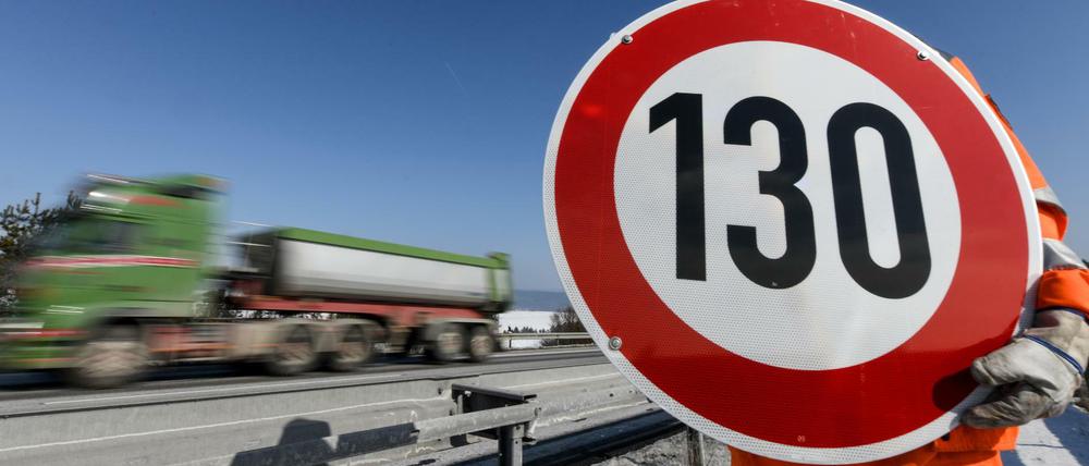 Ein Straßenwärter hält an der Autobahn A81 ein Schild mit der Aufschrift "130" in den Händen.