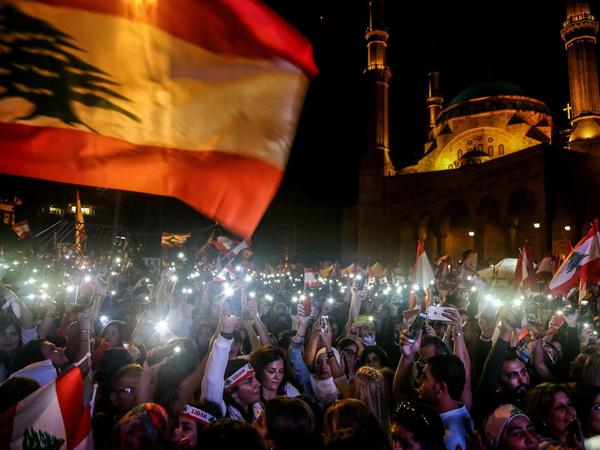 Demonstranten im Libanon schwenken libanesische Nationalflaggen und leuchten mit der Lampe von Handys während einer alternativen Parade in Beirut.