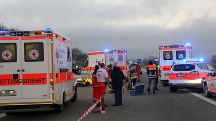 Sanitäter und Feuerwehrleute stehen zwischen mehreren Krankenwagen auf der Autobahn. 