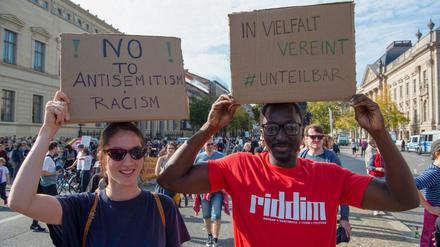 13.10.2019, Berlin: Hannah (26) und Kemo (30) halten Plakate mit der Aufschrift ´No to Antisemitism and Racism» und ´In Vielfalt vereint - #Unteilbar» bei einer Demonstration gegen Antisemitismus auf der Straße des 17.Juni. Veranstalter ist die Initiative ´Unteilbar». Foto: Paul Zinken/dpa +++ dpa-Bildfunk +++