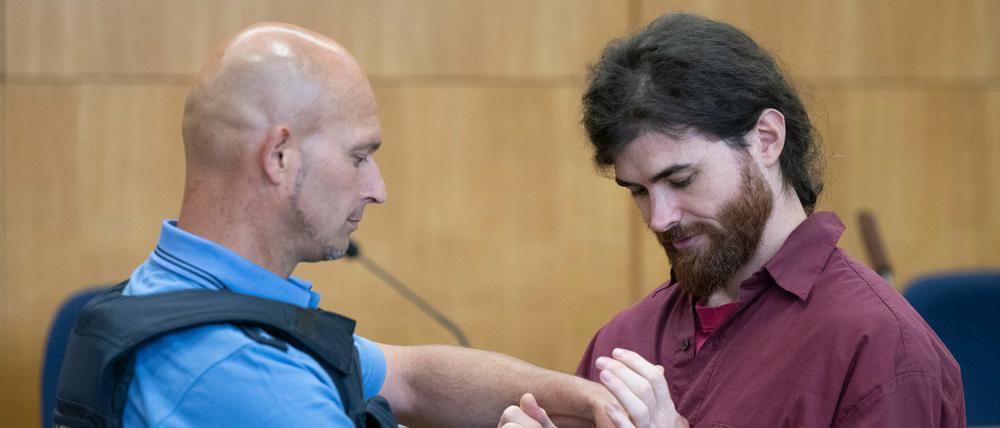 Ein Justizwachtmeister (links) nimmt dem Angeklagten Franco A. auf der Anklagebank im Hochsicherheitssaal des Oberlandesgerichts die Handschellen ab.