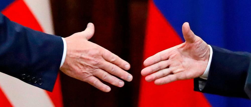 US Präsident Trump (l) und der russische Präsident Putin (r) geben sich die Hand.