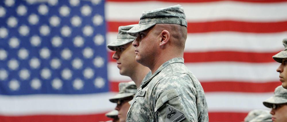 US-Soldaten stehen nach ihrer Ankunft auf der US-Airbase in Wiesbaden-Erbenheim vor einer US-Flagge (Archivbild).