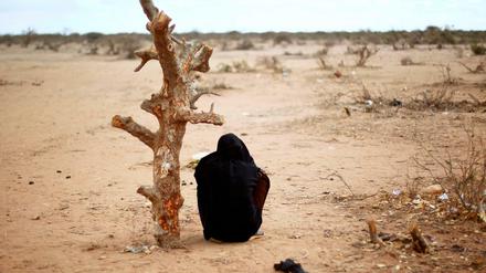 Eine schwangere Frau aus Somalia sitzt in Kenia an einem verdorrten Baum.