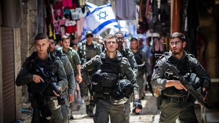 Polizisten sichern Israelis, die mit Flaggen durch die Altstadt Jerusalems gehen.