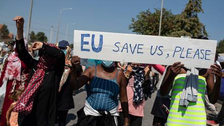 Migrantinnen und Migranten auf Lesbos rufen bei einem Protest Parolen und halten ein Schild mit der Aufschrift: EU, rette uns bitte. 