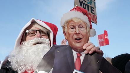 Eine als Weihnachtsmann verkleidete Labour-Unterstützerin hält eine Pappfigur des US-Präsidenten Trump 