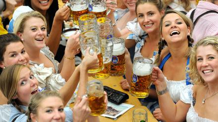 Frauen im Dirndl trinken in einem Festzelt auf dem Oktoberfest in München Bier. 