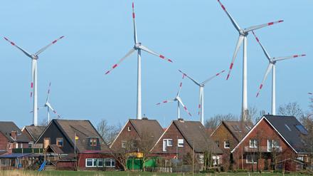 Windkrafträder stehen dicht hinter einer Wohnsiedlung.