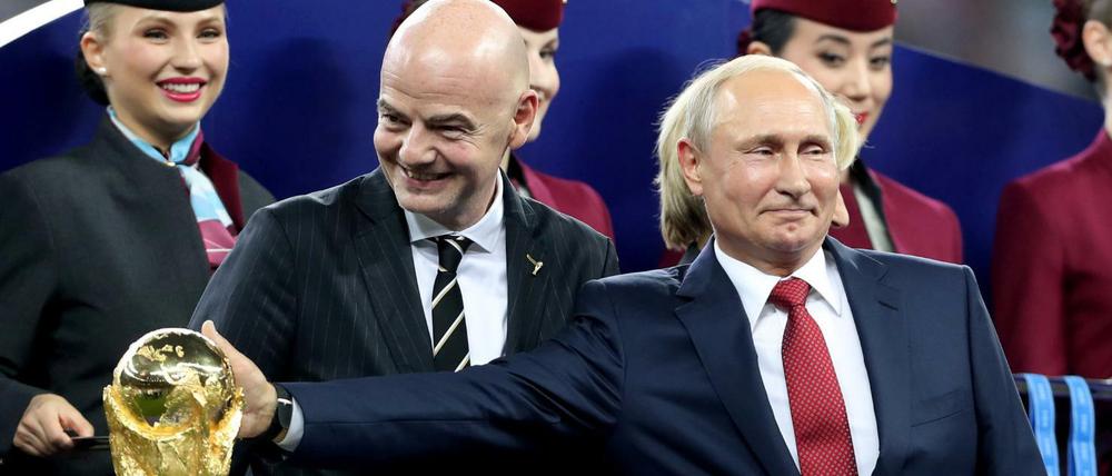 Wladimir Putin (vorne rechts), Präsident von Russland berührt nach dem Spiel neben Gianni Infantino, FIFA-Präsident den WM-Pokal.