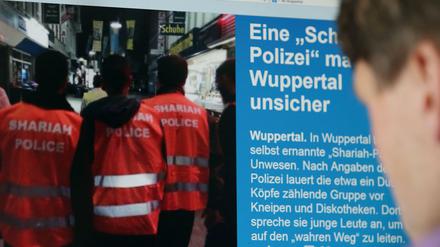 Ein Mann schaut sich in Köln eine Presse-Veröffentlichung über die "Scharia-Polizei an.