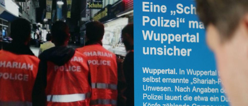 Ein Mann schaut sich in Köln eine Presse-Veröffentlichung über die "Scharia-Polizei an.
