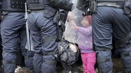 Etappe auf der Flucht. Ein kleines Mädchen berührt im slowenischen Grenzort Rigonce den Schutzschild eines Polizisten. 
