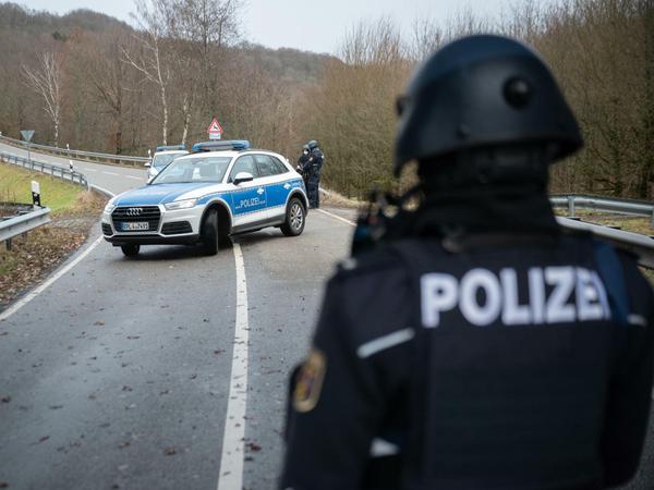 Polizeibeamte stehen an einer Absperrung an der Kreisstraße 22 rund einen Kilometer vom Tatort entfernt.