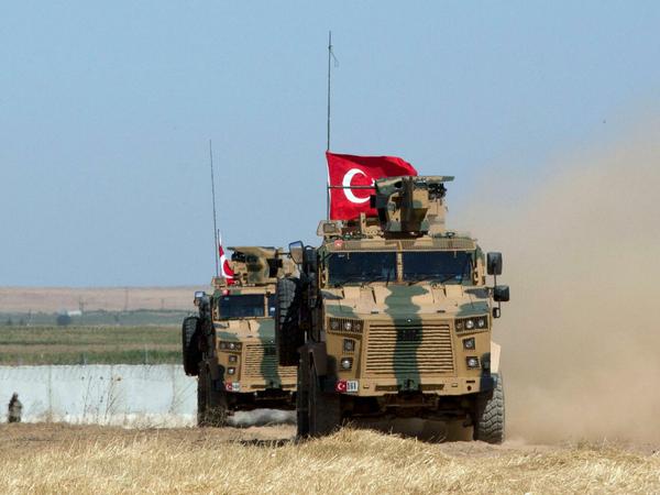 Gepanzerte Militärfahrzeuge der türkischen Streitkräfte fahren auf der syrischen Seite der Grenze zur Türkei entlang.