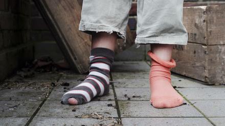 Ein zehn Jahre altes Mädchen steht in abgetragener Kleidung ohne Schuhe in einem Hinterhof in Hamburg