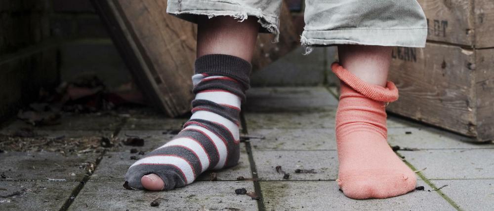 Ein zehn Jahre altes Mädchen steht in abgetragener Kleidung ohne Schuhe in einem Hinterhof in Hamburg