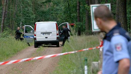 Ein Leichenwagen steht am Freitag in einem abgesperrten Waldstück bei Börnicke (Havelland). Zwei tote Kinder waren in einem ausgebrannten Auto gefunden worden. 