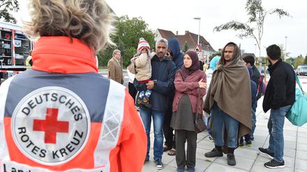 DRK-Helfer weisen Flüchtlingen nach ihrer Ankunft mit einem Zug aus München in Eisenhüttenstadt den Weg zur medizinischen Erstaufnahme. Neonazis wollen in Eisenhüttenstadt demonstrieren.