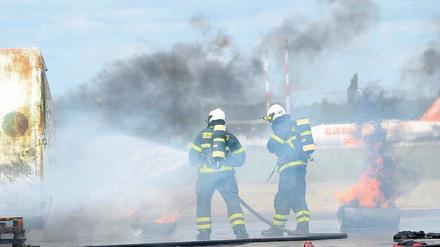 Brennende Flugzeugteile. Feuerwehrleute bei einer Notfallübung auf dem Flughafen Schönefeld. Bei dem Unfallszenario war eine notgelandete Maschine mit einem Tanklastwagen zusammengestoßen und zerschellt.