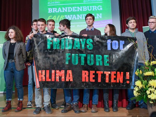 Schüler halten ein Transparent mit der Aufschrift "Fridays for Future Klima Retten!" auf dem Parteitag. Links neben dem Transparent steht die Potsdamer Schülerin Miriam Eichelbaum, am Pult Hannelore Wodtke.