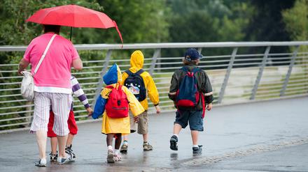 Eine Kindergartengruppe geht am Mittwoch in Potsdam während eines Regenschauers über eine Brücke...