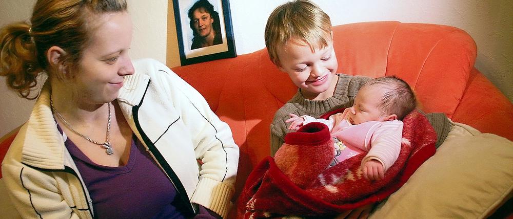 Junge Familie mit Sorgen. Die 20 Jahre alte Nadine Radon sitzt neben ihrem achtjährigen Bruder Florian Niemtschke, der ihr ein Monat altes Baby Zoe hält. Im Hintergrund: Das Bild der jüngst verstorbenen Mutter des Geschwisterpaars. Beide hoffen auf Spenden.