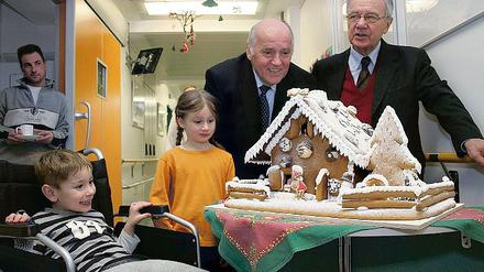 Wie von den Brüdern Grimm gebacken: Ex-Ministerpräsident Manfred Stolpe und Peter Kretschmer, Geschäftsführer des Instituts für Getreideverarbeitung, brachten gestern ein Lebkuchenhaus in die Kinderklinik  sehr zur Freude von Luca und Antonia.
