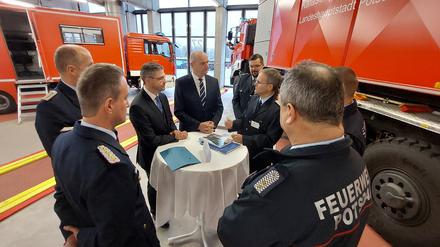 Oberbürgermeister Mike Schubert und Ministerpräsident Dietmar Woidke (beide SPD) unterhalten sich mit Feuerwehrmännern in der Hauptwache in Potsdam.