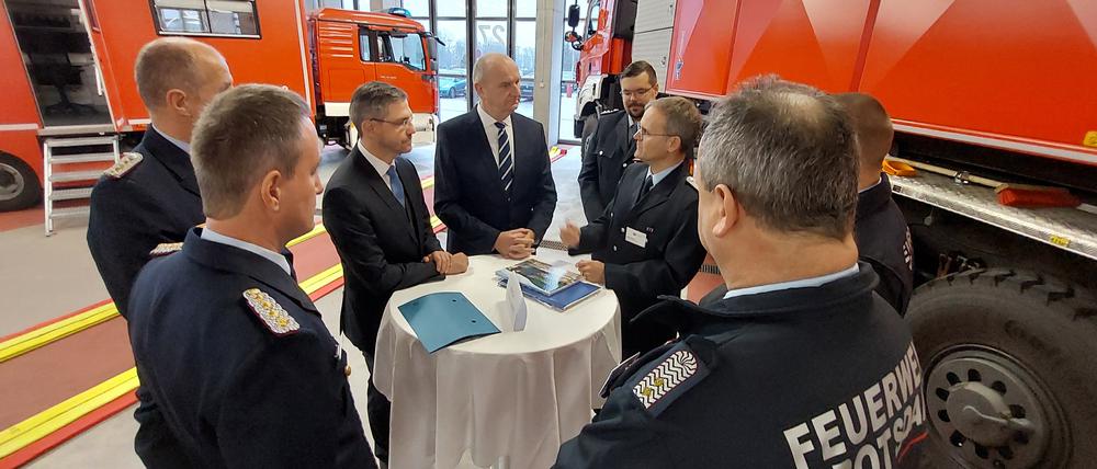 Oberbürgermeister Mike Schubert und Ministerpräsident Dietmar Woidke (beide SPD) unterhalten sich mit Feuerwehrmännern in der Hauptwache in Potsdam.