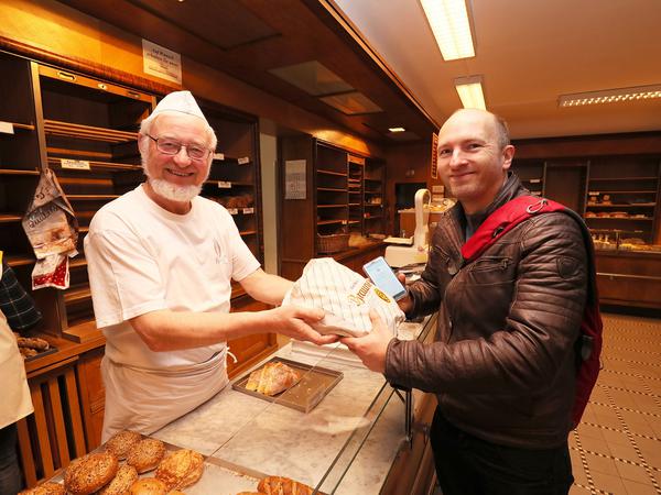Bäckermeister Werner Gniosdorz übergibt Nutzer Robert Haack die neue Überraschungstüte.