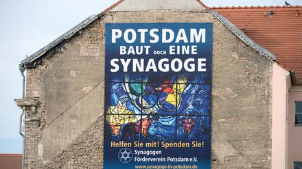 Ein neues Plakat mit der Aufschrift "Potsdam baut doch eine Synagoge" hängt an einer Hauswand in Potsdam. An dieser Stelle ist der Neubau einer Synagoge geplant.
