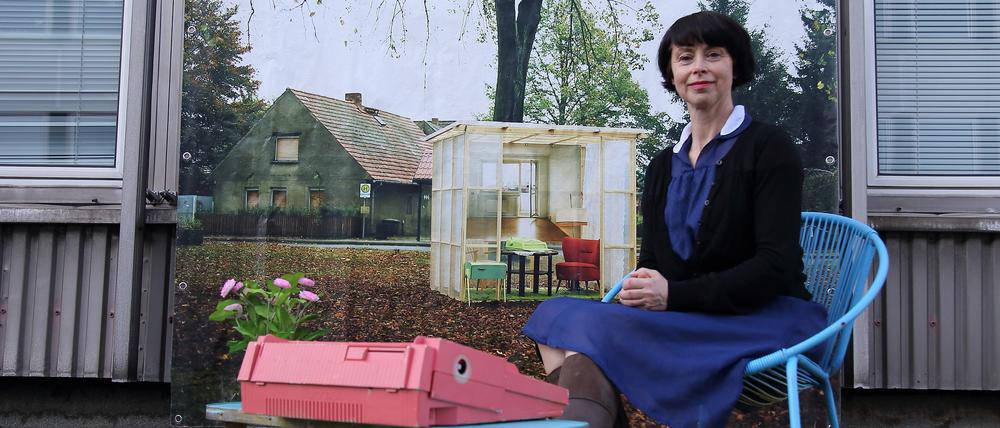 Die Fotografin Kathrin Ollroge sitzt vor einem Transparent, das ihre mobile Wohnrauminstallation zeigt, auf einem Dach im Rechenzentrum in Potsdam.