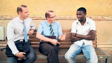 Religion auf der Parkbank. Der 25-jährige Brian aus Kamerun, der in Deutschland Asyl sucht, unterhält sich mit Zeugen Jehovas über die Suche nach dem Paradies.