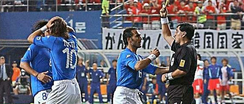 Saubermann auf Abwegen. Schiedsrichter Moreno wird während des WM-Spiels Südkorea – Italien 2002 von den Italienern bedrängt, nachdem er Francesco Totti Gelb gezeigt hat.