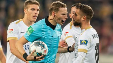 Diskussion. Die Spieler des SV Wehen-Wiesbaden umringen Schiedsrichter Martin Petersen.
