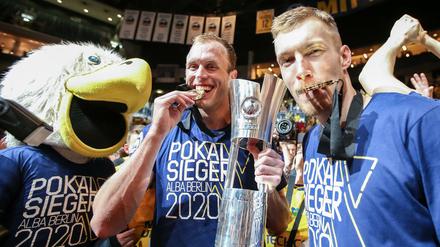 Endlich mal was Bissfestes. Luke Sikma (Mitte) feiert den Pokalsieg mit Niels Giffey (rechts) und dem Maskottchen. 