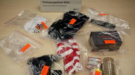 Sichergestellte Sturmhauben, pyrotechnisches Material, Schlagstöcke und ein Ortungsgerät liegen im Polizeipräsidium auf dem Tisch. Nach dem Angriff auf einen Fanbus des Fußball-Zweitligisten 1. FC Union Berlin in Köln hat die Polizei 28 Personen festgenommen. +